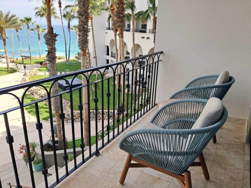Two chairs and a small table on the balcony facing the sea in Los Cabos.