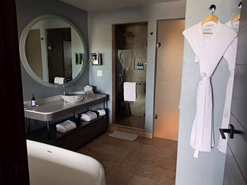 Bathroom with tub, shower, sink and robes.