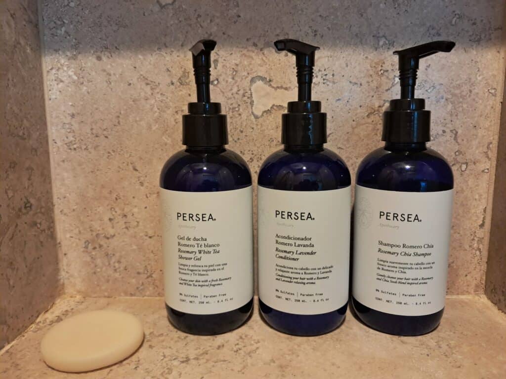 Persea body wash, shampoo, conditioner, and bar of soap on shelf in the shower.
