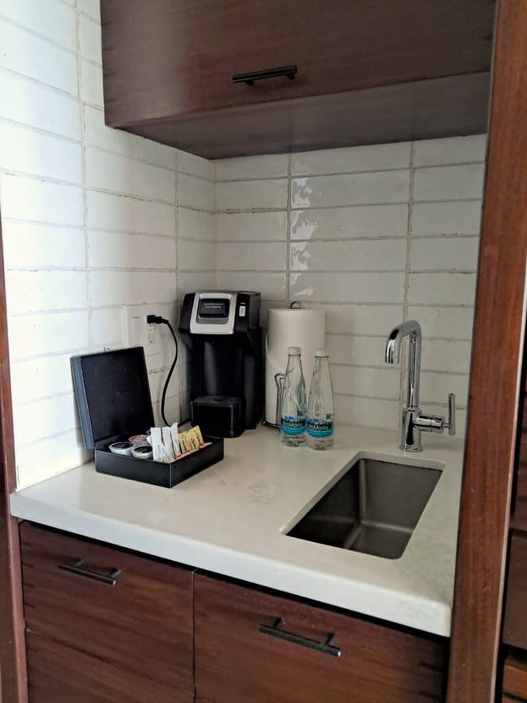 Small kitchenette with sink, coffee maker and pods.