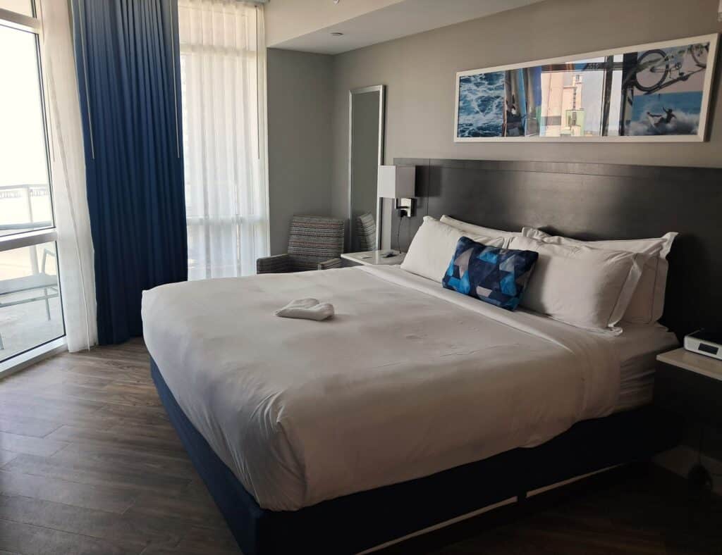 King-size bed with a corner chair and windows in the master bedroom.