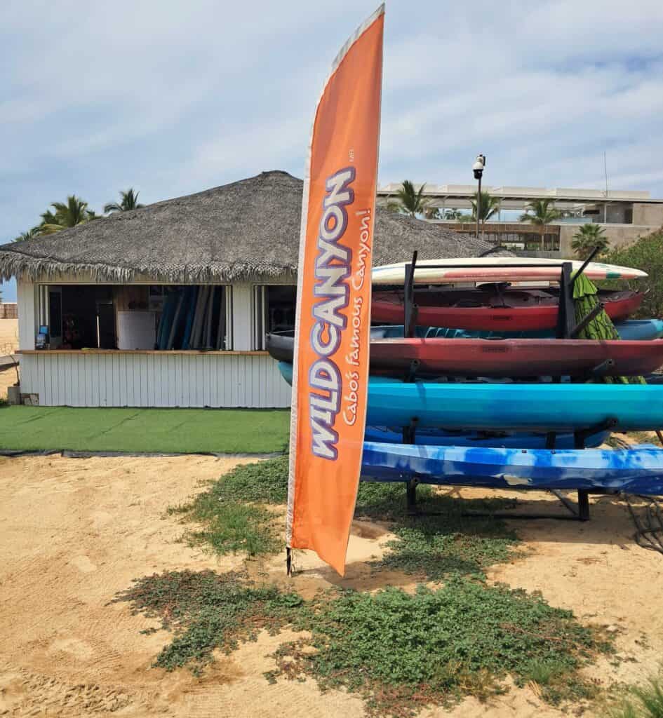 Wild Canyon adventure with sign, kayaks, and storefront on the beach next to the Hilton Los Cabos.
