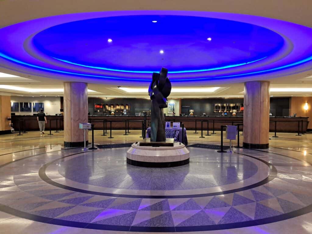 Lobby at the Hilton Midtown Hotel with a statue in the center and check-in desks in the background.