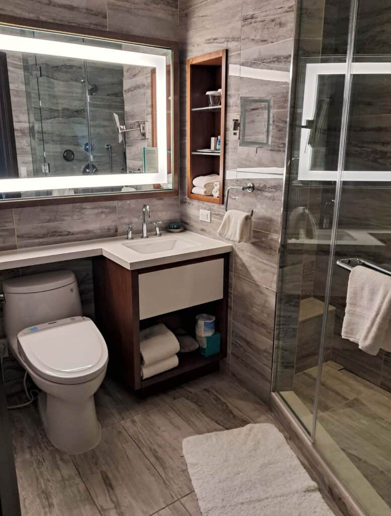 Bathroom with sink, toilet, shower and mirror in the studio room.