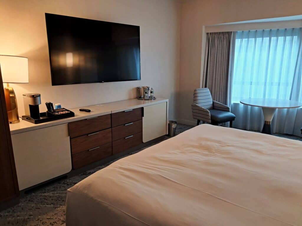 The Residences by Hilton Club review of a studio room with a tv hanging on the wall, Keurig coffee maker, long bureau and a chair.