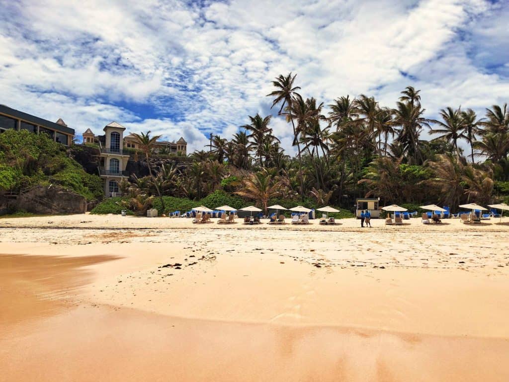 The Crane Beach with coral sand and lounge chairs with umbrellas and the glass fronted elevator to the left.