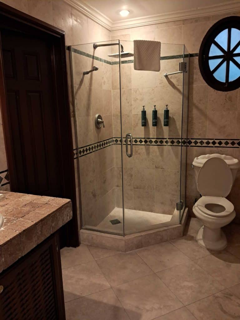 Villa bathroom with walk in shower, toilet and sink and door to bedroom.