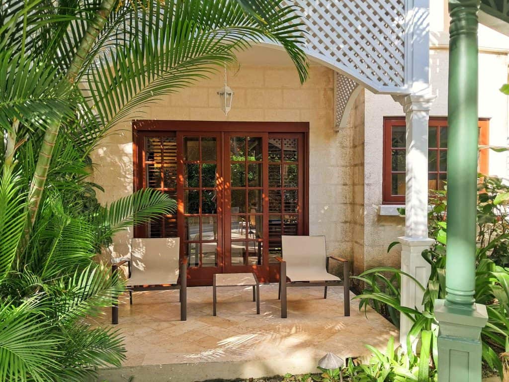 Two chairs and table in front of sliding doors to villa on the porch.