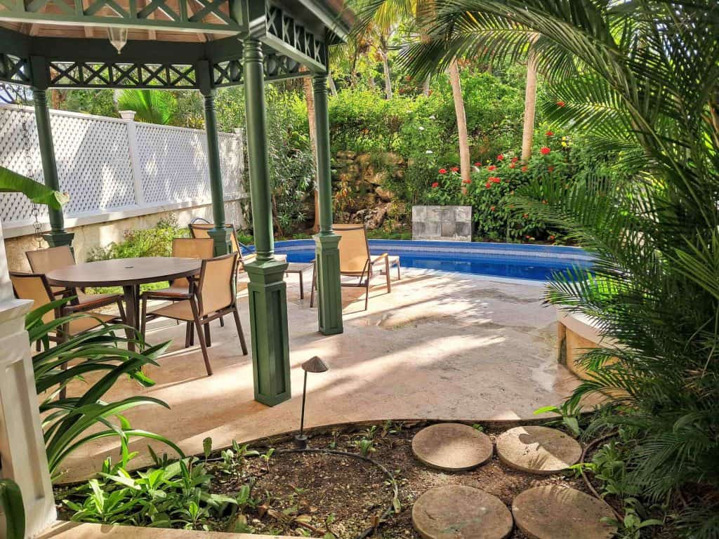 Tropical garden with swimming pool, gazebo, table, chairs and 2 lounge chairs at The Crane Resort Barbados.