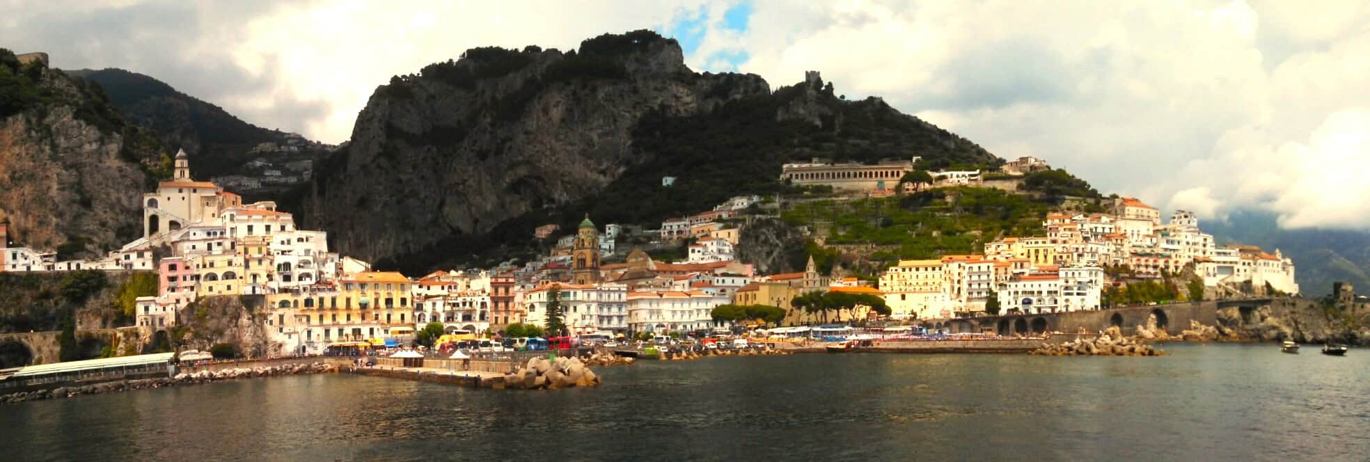 View of the town of Amalfi from the water with mountains in the background in Italy travel.
