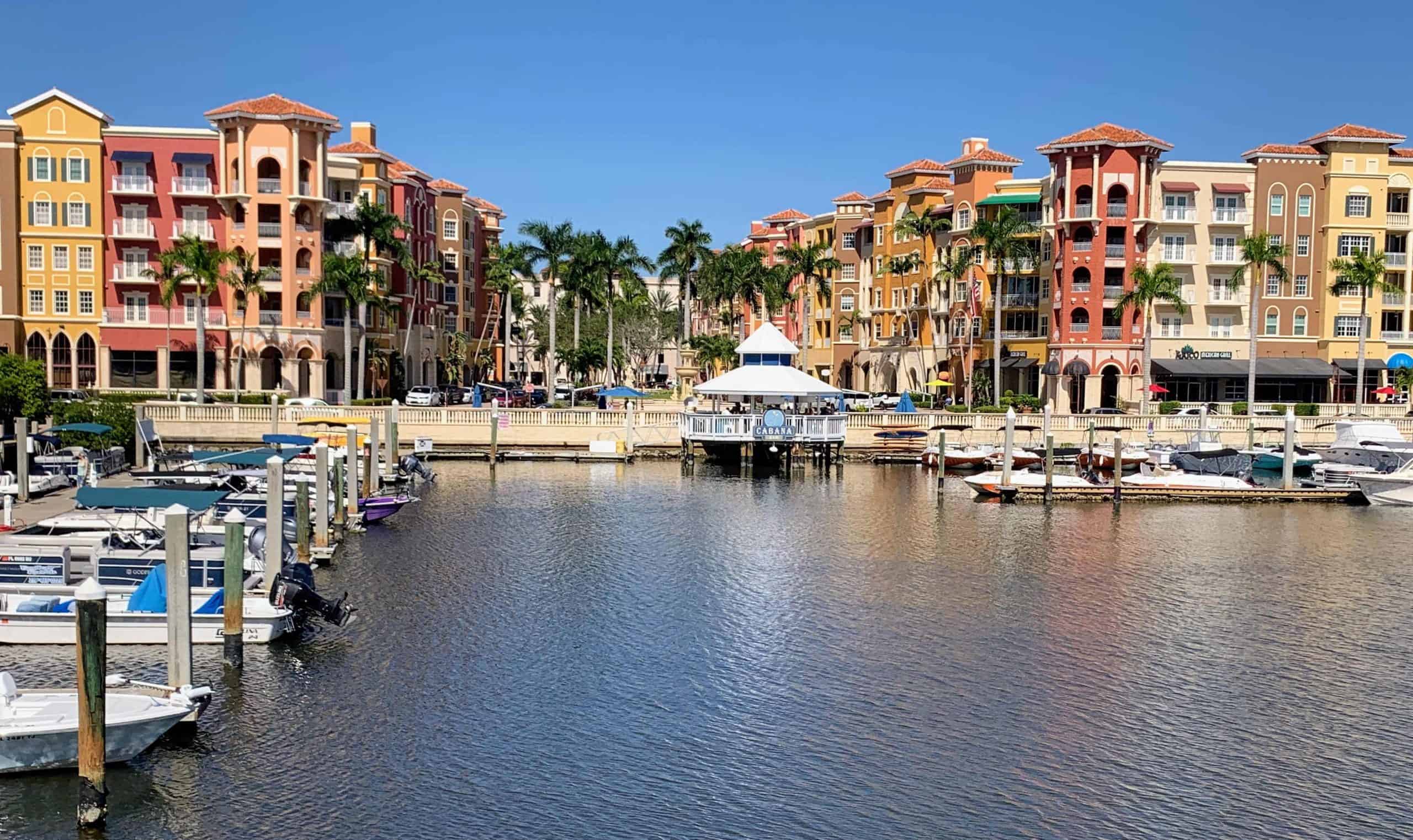 Water with palm trees, pastel-colored buildings and a boat marina in Southwest Florida.