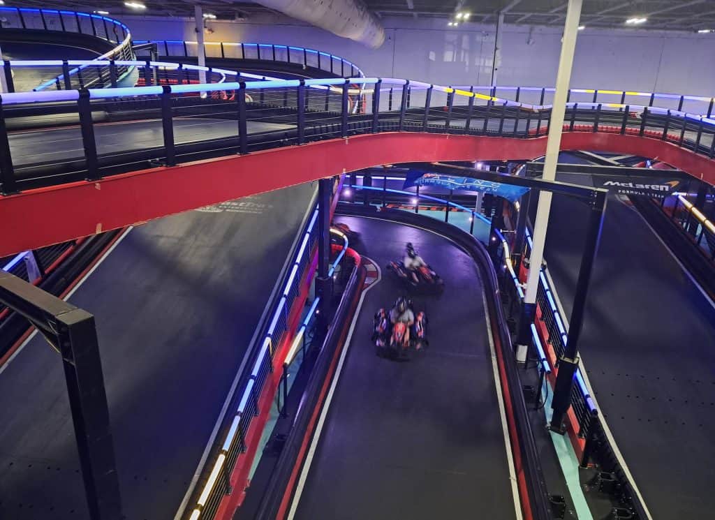 Multi-level racetrack with 2 go carts racing down the lower track.