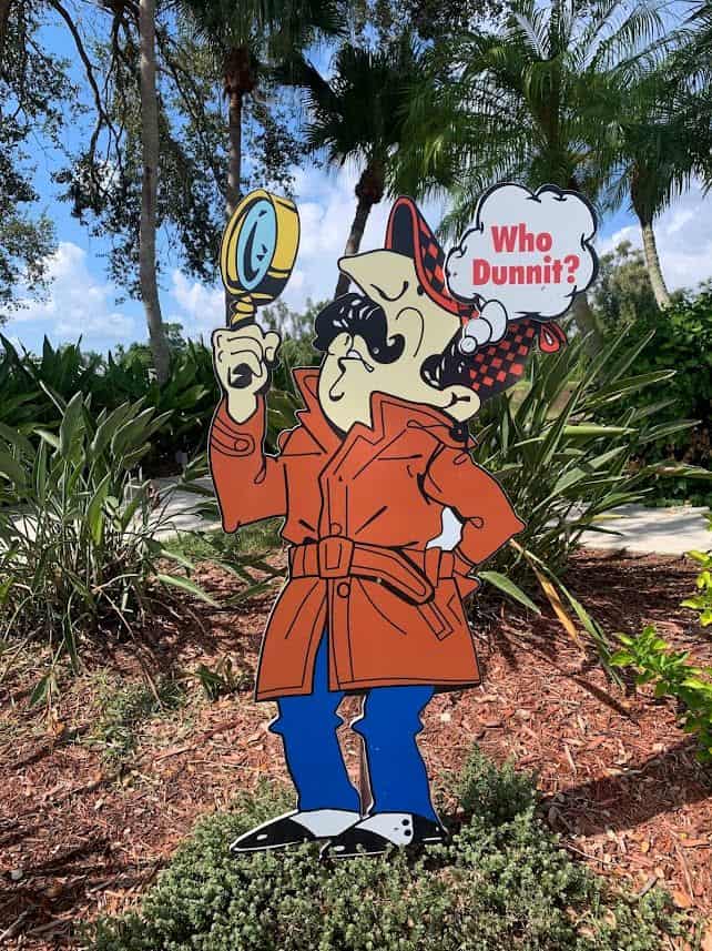 Who dunnit sign with an inspector holding a magnifier glass.