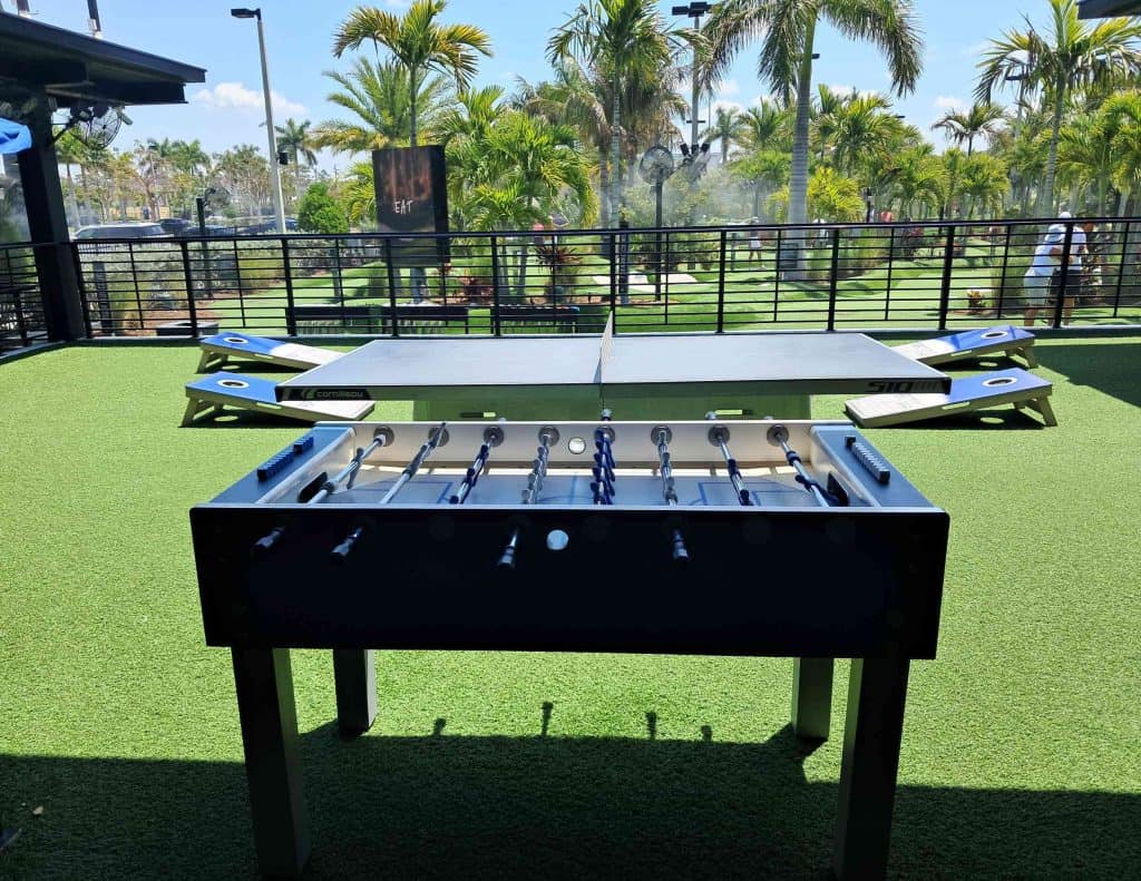 Fuzz ball table and corn hole in activities area at PopStroke.