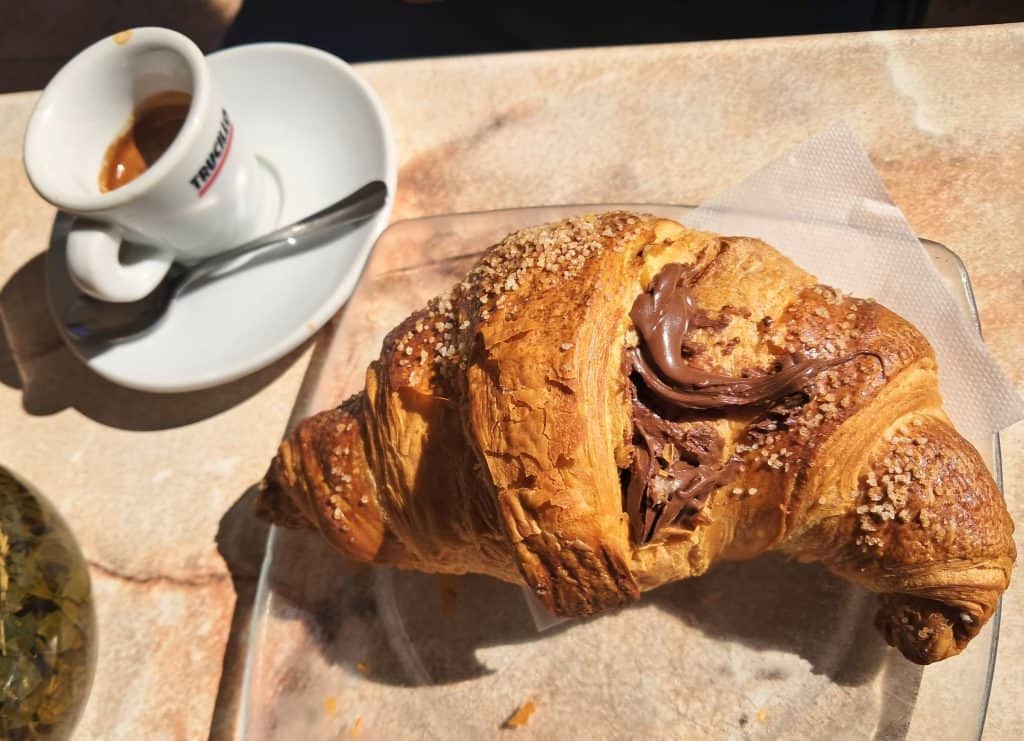 An espresso with a chocolate cornetto on a table at a cafe in San Nicola Arcella Italy.